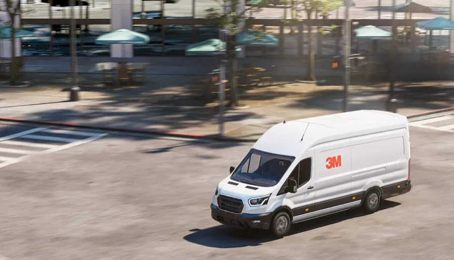 White cargo van with 3M Cooling Film applied to the roof driving through a sunny city street